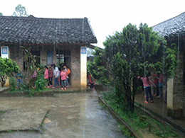 暴雨中，教室里出現(xiàn)漏水情況，學生們在屋檐下避雨